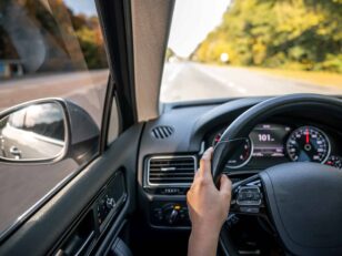 Woman driver's hands on the steering wheel inside the car.