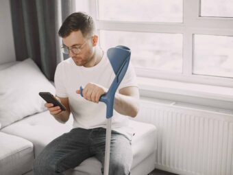 Young man with walking stick talk by phone indoors